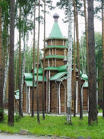 Wooden Chapel with green roofs, seen through trees