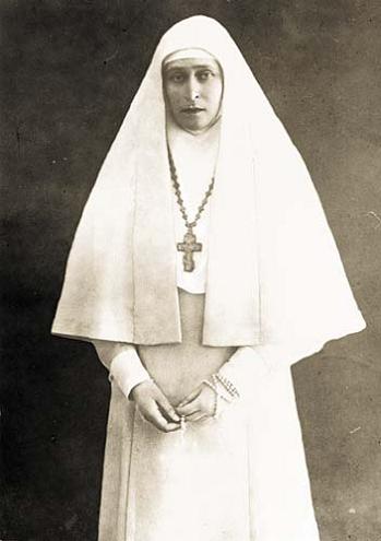 Grand Duchess Elizabeth Feodorovna in the habit of a nun: white tunic and wimple, and a large metal cross hanging from the neck.